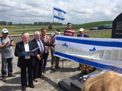 Holocaust survivor Israel Zinman speaks as a parchment written by a scribe, recording the names of those murdered in Velyki Mezhyrichi, was unfurled at the mass grave killing site in the village.