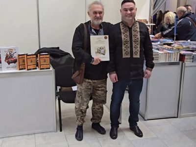 Владислав Гриневич, Регіональний менеджер UJE в Україні дарує книжку «Євреї та українці: тисячоліття співіснування» Сашку Лірнику — українському казкарю-лірнику, музиканту, актору та телеведучому.