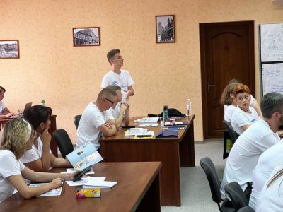The participants of the summer school held by the Verba Magistri Methodology Lab, lecturers, and teachers from various Ukrainian educational institutions perusing UJE's latest publication, the catalogue of "The All-Ukrainian Children's Drawing Competition 2021/2022," 3 August 2023, Uzhhorod. 