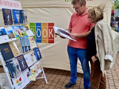 На книжковому стенді «Українсько-Єврейської Зустрічі»: відвідувачі книжкового фестивалю «VinBookFest» з цікавістю знайомляться з книжками, виданими за підтримки UJE. 14–15 вересня 2024 року, місто Вінниця.