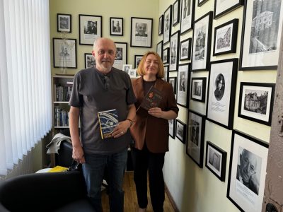 Left to right: Ukrainian writer Vasyl Makhno and Mariana Maksymiak, Director of the Agnon Literary Center in Buchach, Ukraine. At the Agnon center, which is located in Buchach’s city library, on 24 May 2026. Makhno is holding his novel Eternal Calendar, which won UJE’s inaugural Encounter: The Ukrainian-Jewish Literary Prize in 2020. Maksymiak is holding Makhno’s newest book, “The Angel and The Donkey. With Poems About Fire and Water”.